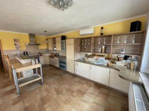 a large kitchen with white cabinets and a table at Gästezimmer zum Sonnenhof in Zahna-Elster