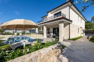 a house with a swimming pool and an umbrella at Villa Laura in Malinska