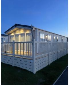 a house with a white fence on the grass at 59 Cliff Field in Hopton on Sea