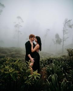 a man and woman kissing in a foggy field at Tea and Experience Factory - Thema Collection in Mandaran Newara