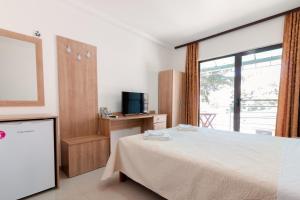 a bedroom with a bed and a tv and a window at Villa Ljupce in Ohrid