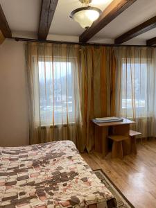 a bedroom with a bed and a desk and a window at Садиба у Віталія in Volovets