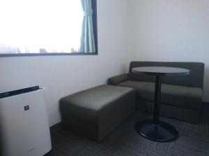 a room with a chair and a table and a stool at Terminal Hotel Matsuyama in Matsuyama