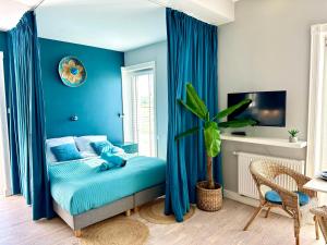 Un dormitorio azul con una cama con cortinas azules. en Sunset Apartments Kropla Baltyku, en Darłówko