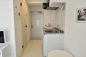 Elle comprend une petite salle de bains blanche pourvue d'un lavabo et de toilettes. dans l'établissement CRYSTAL ＆ RESORT FUKUOKA, à Fukuoka