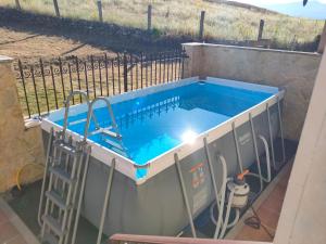 a swimming pool with a ladder next to a fence at Casa rural Con Calma in Zarzuela del Monte