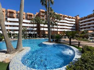 a swimming pool with palm trees in front of a building at Arena Center in Roquetas de Mar