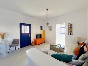 Una sala de estar con un sofá y una puerta azul. en Karpimo North - Sunset view - Private Jacuzzi - up to 4pp, en Fira