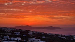 Una puesta de sol sobre una ciudad con el océano y los edificios. en Karpimo North - Sunset view - Private Jacuzzi - up to 4pp, en Fira