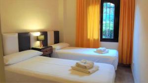 two beds in a hotel room with towels on them at Apartamento de dos dormitorios y un baño con piscinas y jardines cercano a la playa in Estepona