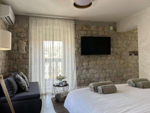 a bedroom with a bed and a tv on a stone wall at Guest House Exalto in Trogir