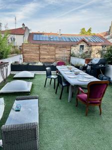a patio with a table and chairs on the grass at LOFT A 15 MINUTES DE PARIS ET 30 MINUTES DISNEY in Parc Saint-Maur