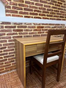 a wooden desk with a chair next to a brick wall at Pilachhen Community Homestay Thachyacha Room 2A in Pātan