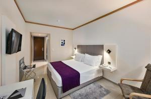 アルブフェイラにあるRocamar Exclusive Hotel & Spa - Adults Onlyのベッドと椅子のあるホテルの部屋