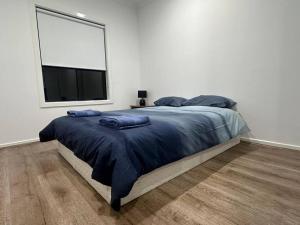 a bedroom with a bed with blue sheets and a window at Stockmans in Truganina