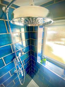 a blue tiled bathroom with a shower with a light at 2-Bed Village Country Cottage with Free Parking and Pub - County Durham in Newton Aycliffe +27 photos