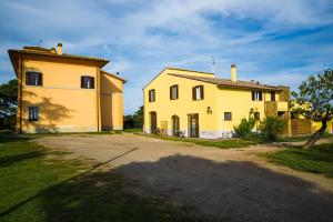 un grande edificio giallo accanto a una casa di Agriturismo Sensi a Tuscania