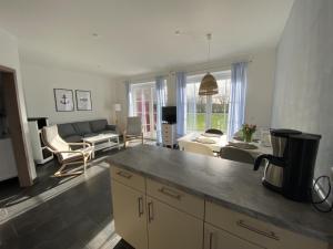 a kitchen and living room with a couch and a table at Haus Am Dorfteich D mit Spielplatz in Fehmarn