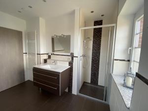 a white bathroom with a sink and a shower at Haus Am Dorfteich D mit Spielplatz in Fehmarn +11 photos
