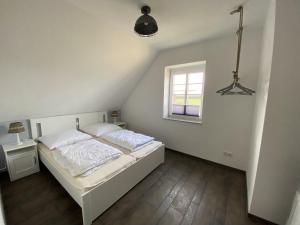 a bedroom with a white bed and a window at Haus Am Dorfteich D mit Spielplatz in Fehmarn