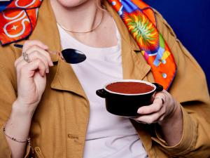 a woman holding a cup of coffee with a spoon at TRIBE Milano Malpensa in Vizzola Ticino