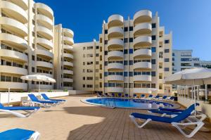 una piscina di fronte a un hotel con sedie e ombrelloni di TURIM Algarve Mor Apartamentos Turísticos a Portimão