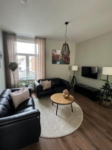 a living room with a black leather couch and a table at La Estancia Latinos in Valkenburg