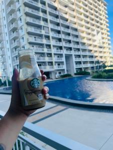 a person holding a beer in front of a building at Gina Staycation The Atherton DMCI Parañaque in Manila +4 photos
