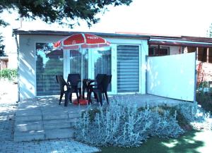 a patio with a table and chairs under an umbrella at Fenyőmag Apartmanház in Balatonakali