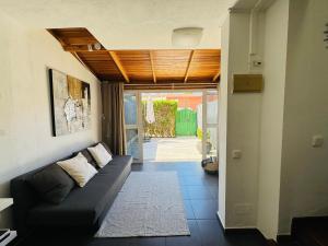 a living room with a black couch and a doorway at Bungalow Casita in Maspalomas +14 photos