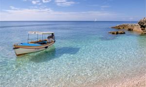a man sitting on a boat in the water at Apartments Punta Milna in Hvar