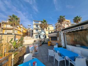 a patio with blue tables and chairs and buildings at Maniel Beach Hotel in Letojanni