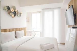 a white bedroom with a large white bed and a window at Homey and Good Choice Studio Tokyo Riverside PIK 2 Apartment By Travelio in Rawalembang
