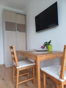 a wooden table with two chairs and a television on a wall at APARTAMENTY BAŁTYCKA 4d in Rowy