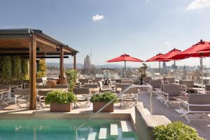 a rooftop patio with chairs and umbrellas and a pool at Majestic Hotel & Spa Barcelona GL in Barcelona