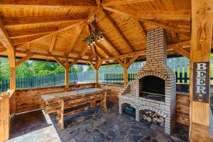 an outdoor patio with a fireplace and a wooden roof at Country Relax Resort in Săcuieu