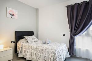 una camera da letto con un letto con una sedia nera e una finestra di El Muelle a Gran Tarajal