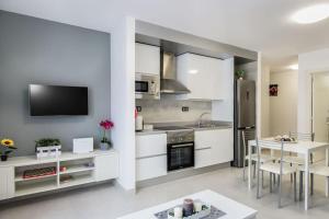 una cucina con armadi bianchi, tavolo e televisore di El Muelle a Gran Tarajal