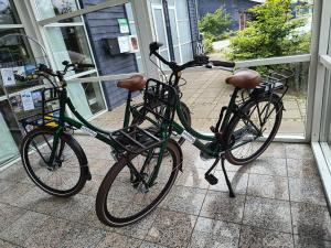 due biciclette parcheggiate l'una accanto all'altra di fronte a un negozio di Hotel Sleep2Night a Helsingør