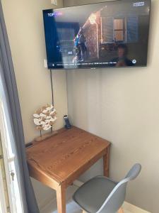 ein Fernseher, der über einem Holztisch mit einem Stuhl hängt in der Unterkunft Chauveau - entre port et plage in Saint-Martin-de-Ré