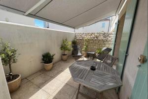 eine Terrasse mit einem Tisch, Stühlen und Topfpflanzen in der Unterkunft Chauveau - entre port et plage in Saint-Martin-de-Ré