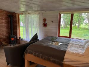 a bedroom with a bed and a chair and a window at sun& relax- TINYHOUSE in Sõitme
