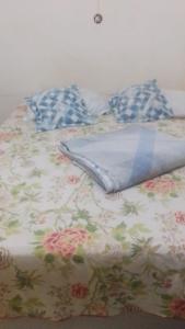 a bed with a floral blanket and pillows on it at Caminhos do Mar Hostel in Porto De Galinhas
