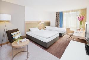 um quarto de hotel com duas camas e uma mesa em Mövenpick Hotel Zürich-Regensdorf em Regensdorf