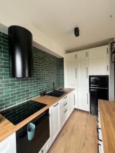 a kitchen with white cabinets and a black appliances at Colorado in Gdańsk +16 photos