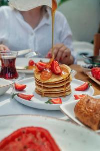 a person is eating pancakes with strawberries on a table at Kassandra Boutique Hotel in Oludeniz