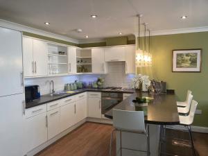 a kitchen with white cabinets and a table with chairs at The Bijou on Park View in Harrogate
