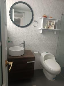 ein Badezimmer mit Toilette, Waschbecken und Spiegel in der Unterkunft Apartahotel Acuña in Moniquirá