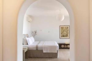 een witte slaapkamer met een bed in een witte kamer bij Villa Calithenean in Mykonos-stad +46 foto's