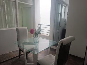 ein Esstisch aus Glas mit einer Vase mit Blumen darauf in der Unterkunft Apartahotel Acuña in Moniquirá